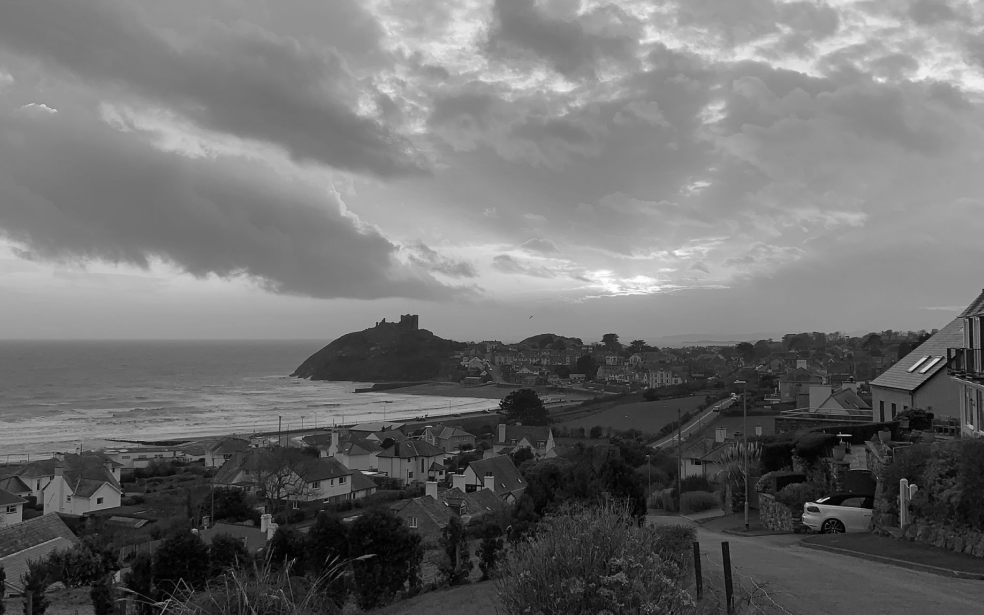 Vista de uma cidade costeira com mar e castelo ao fundo